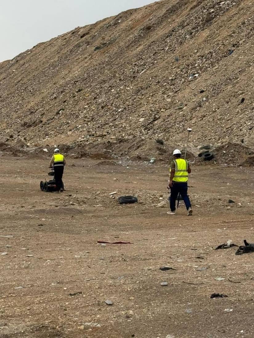 طاقم مسح GPR من شخصين يمشي على خط مسح بوحدة رادار وعصا GNSS متحركة عبر المكب