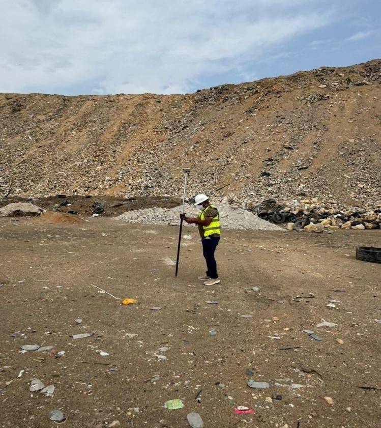 مهندس جي بي آر سيرفي يستخدم عصا GNSS متحركة بدقة RTK لإنشاء نقاط تحكم مساحية عبر موقع المكب