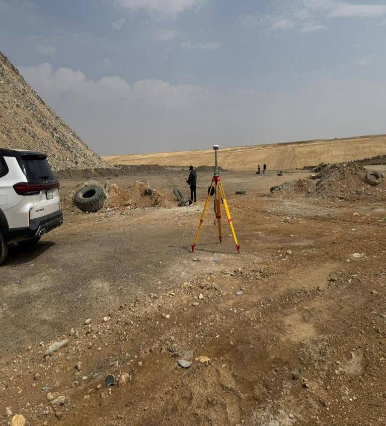 جهاز محطة شاملة مُثبَّت على حامل ثلاثي القوائم في موقع المكب، مع مركبة ميدانية وطاقم في الخلفية